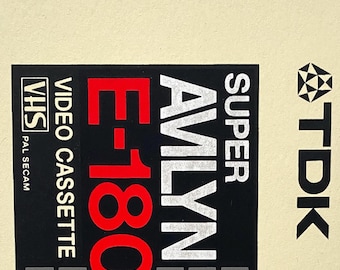 May include: A vintage TDK Super Avilyn E-180 VHS video cassette tape. The label features the text "HIGH OUTPUT HIGH RESOLUTION", "VIDEO CASSETTE", and "180 min. of video recording and playback". The tape has a black, red, green, and blue color bar.