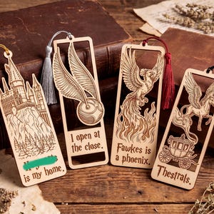 May include: Four rectangular wooden bookmarks with laser-engraved designs and colored tassels. The designs feature a castle, a winged ball with the text 'I open at the close.', a phoenix with 'Fawkes is a phoenix.', and a carriage with 'Thestrals.'