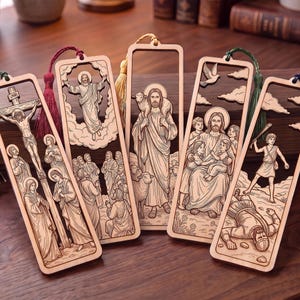 Puede incluir: Cinco marcapáginas rectangulares de madera con escenas religiosas cortadas con láser, incluyendo la crucifixión, la ascensión, el Buen Pastor, Jesús con niños, y David y Goliat. Cada marcapáginas tiene una borla de color en la parte superior.