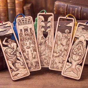 Könnte beinhalten: Fünf rechteckige Lesezeichen aus Holz mit lasergeschnittenen biblischen Szenen. Jedes Lesezeichen hat eine farbige Quaste: rot, blau, grün, gelb und lila. Die Motive zeigen Samson mit einem Löwen, das Abendmahl, Mose bei der Teilung des Meeres, die Bergpredigt und Jona im Bauch eines großen Fisches.