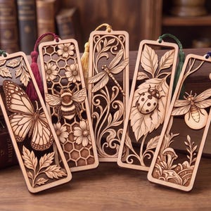 Könnte beinhalten: Fünf rechteckige Lesezeichen aus Holz mit filigranen Laserschnitt-Motiven von einem Schmetterling, einer Biene auf einer Wabe, einer Libelle, einem Marienkäfer auf einem Blatt und einem Glühwürmchen. Jedes Lesezeichen hat eine farbige Quaste.