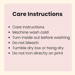 Pu&ograve; includere: Un cartello rettangolare rosa chiaro con testo nero che recita: Care Instructions, Machine wash cold, Turn inside out before washing, Do not bleach, Tumble dry low or hang dry e Do not iron directly on print. Il testo &egrave; centrato.