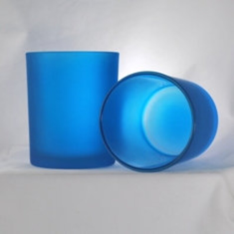 May include: Two frosted blue glass candle jars. The jars are cylindrical and have a smooth, matte finish.