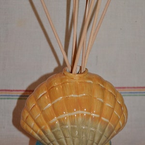 May include: A ceramic seashell diffuser with a starfish design and a set of wooden diffuser sticks. The seashell is painted in shades of yellow, green, and blue.