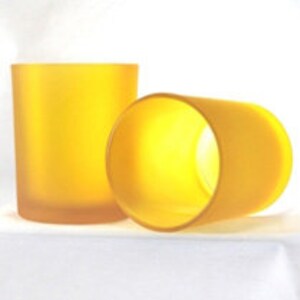 May include: Two frosted yellow glass candle jars. The jars are cylindrical and have a smooth, matte finish.