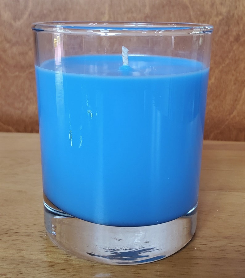 May include: A blue candle in a clear glass jar with a white wick.