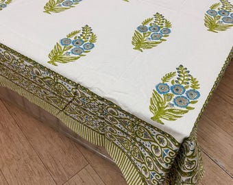 May include: White tablecloth with a repeating pattern of blue and green floral bouquets. The border features a green and white striped design with a detailed floral pattern. The tablecloth is made of a soft, likely cotton, fabric.