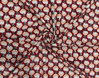 May include: A close-up of a fabric with a repeating floral pattern. The flowers are peach and white, set against a deep red background. The fabric is folded, creating a textured appearance.