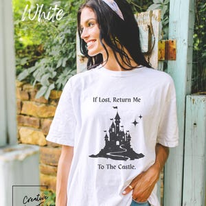 May include: White t-shirt featuring a black castle graphic and the text "If Lost, Return Me To The Castle." The shirt also has the text "Creative Lee Tees" in a black box. The word "White" is written in cursive at the top of the image.