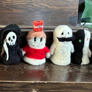 May include: A selection of handmade yarn dolls, each with a distinct design. The dolls feature characters with blue hair, red hoods, yellow outfits, a Grim Reaper, a TNT-topped figure, a ghost with a moustache, and a black and white character.