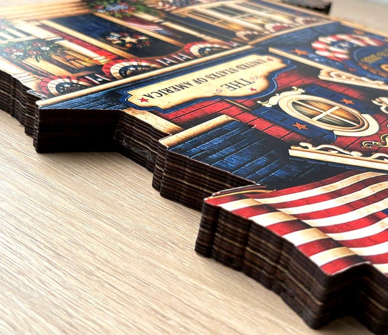 May include: A multi-layered wooden wall art piece featuring a patriotic theme with red, white, and blue colors. The design includes an American flag, architectural details, and a banner with the text THE UNITED STATES OF AMERICA printed.