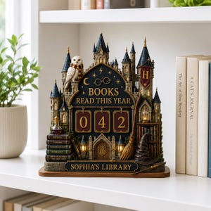May include: A decorative tabletop book tracker shaped like a castle, featuring a white owl, a broomstick, and a sorting hat. The display includes the text "BOOKS READ THIS YEAR", "SOPHIA'S LIBRARY", and three rotating number tiles showing 042.
