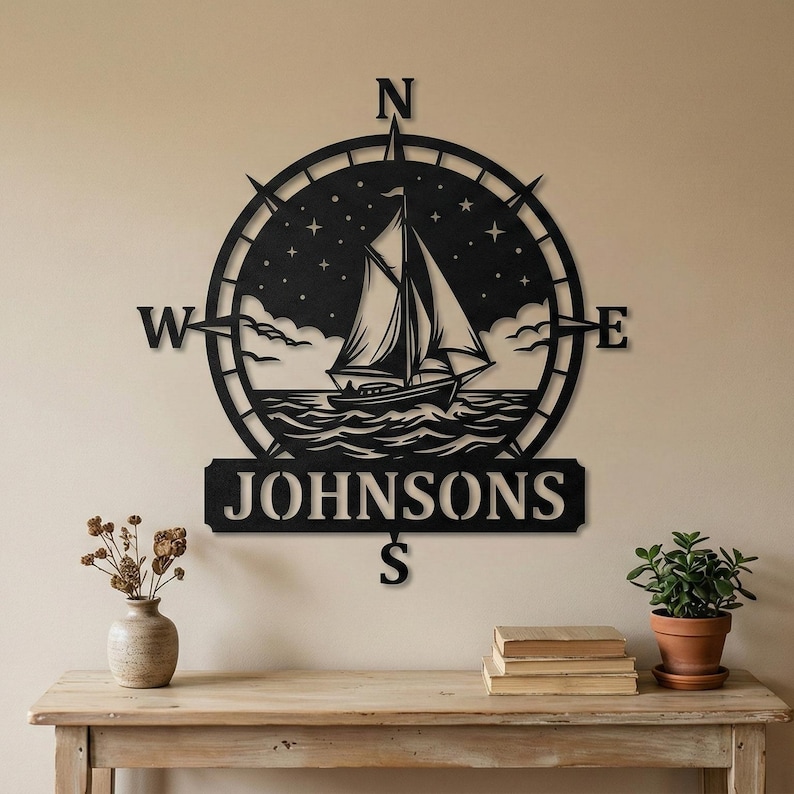 Personalized nautical compass metal wall decor featuring a sailboat at sea with custom family name, designed in a round coastal style. Available in multiple sizes and finishes including black, gold, silver, bronze, and white. Ideal for living rooms, entryways, beach houses, lake houses, or outdoor walls. Easy to hang and weather resistant. A unique gift for sailors, ocean lovers, housewarming, weddings, or modern coastal home decor.