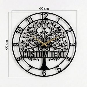 Puede incluir: Un reloj de pared de metal negro, de 60 cm de diámetro, con un diseño de árbol y el texto "CUSTOM TEXT". El reloj tiene manecillas doradas y un marco circular con números que marcan las horas.