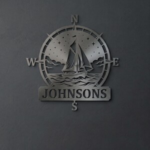 Personalized nautical compass metal wall decor featuring a sailboat at sea with custom family name, designed in a round coastal style. Available in multiple sizes and finishes including black, gold, silver, bronze, and white. Ideal for living rooms, entryways, beach houses, lake houses, or outdoor walls. Easy to hang and weather resistant. A unique gift for sailors, ocean lovers, housewarming, weddings, or modern coastal home decor.