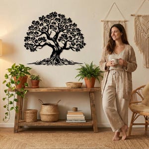 Könnte beinhalten: Schwarze Metall-Wandkunst in Form eines Baumes mit detaillierten Blättern und Ästen. An einer hellen Wand über einem Holztisch angebracht. Der Tisch zeigt Topfpflanzen, Bücher und geflochtene Körbe, was eine natürliche, rustikale Ästhetik erzeugt.