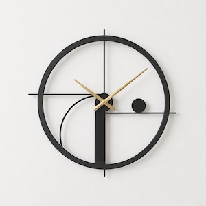May include: A circular wall clock featuring a black metal frame with a vertical bar, a curved arc, and a small solid circle. The clock has two gold-colored hands at the center, extending outward to indicate time against the open, skeletal design.