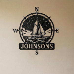Personalized nautical compass metal wall decor featuring a sailboat at sea with custom family name, designed in a round coastal style. Available in multiple sizes and finishes including black, gold, silver, bronze, and white. Ideal for living rooms, entryways, beach houses, lake houses, or outdoor walls. Easy to hang and weather resistant. A unique gift for sailors, ocean lovers, housewarming, weddings, or modern coastal home decor.