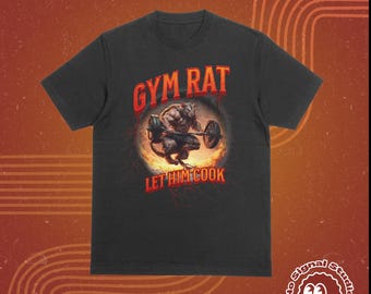 May include: Dark gray t-shirt with the text "GYM RAT" in red, above an illustration of a muscular rat lifting weights. The phrase "LET HIM COOK" is below the illustration. The shirt has a crew neck and short sleeves.
