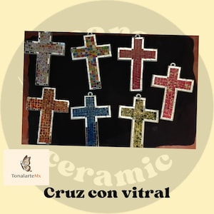 May include: A collection of mosaic crosses in various colors, including red, blue, and gold. Each cross is made of small, colorful tiles and has a silver loop for hanging. The text "Cruz con vitral" is at the bottom.