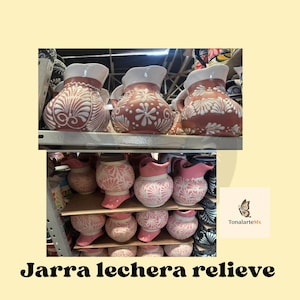 Puede incluir: Jarras de cerámica en tonos rojizos y rosas, adornadas con diseños florales blancos. Las jarras tienen bordes y asas blancas. La imagen incluye el texto "Jarra lechera relieve".