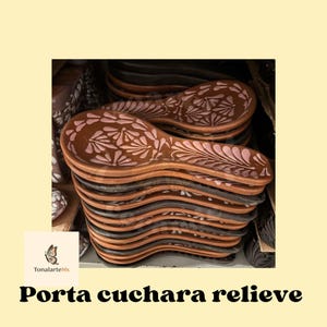 May include: A stack of brown ceramic spoon rests with a floral design in pink. The spoon rests have a curved shape and are stacked on top of each other. The text "Porta cuchara relieve" is at the bottom.