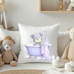 Puede incluir: Cojín cuadrado blanco con un oso de dibujos animados en una bañera morada llena de burbujas. Una toalla morada cuelga a un lado. Se ven otros osos de peluche.