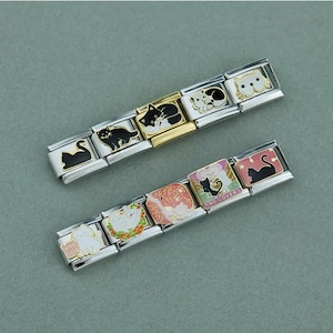 Könnte beinhalten: Zwei Edelstahl-Charm-Armbänder mit Katzenmotiven. Die Charms zeigen schwarze, weiße und goldene Katzen in verschiedenen Posen, darunter Silhouetten und verspielte Szenen. Einige Charms haben rosa und rote Akzente, und ein Charm hat den Text "THE LOVERS".