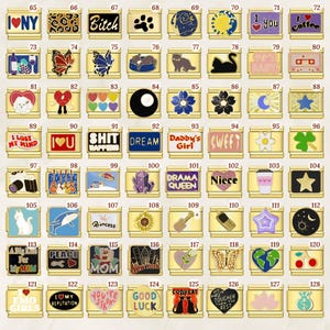 Puede incluir: Una colecci&oacute;n de colgantes de abalorios dorados con varios dise&ntilde;os, incluyendo texto, animales y s&iacute;mbolos. Los abalorios presentan frases como "I Love You", "Dream" y "Good Luck", junto con im&aacute;genes de gatos, mariposas e instrumentos musicales.