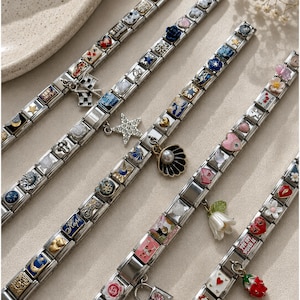 Puede incluir: Cuatro pulseras de eslabones modulares en tono plateado con una variedad de dijes de esmalte de colores, incluyendo corazones, estrellas, flores, una concha con una perla, una bandera a cuadros y varios símbolos. Cada pulsera tiene eslabones metálicos.