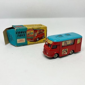 May include: A vintage Corgi Toys Chipperfields Circus Mobile Booking Office toy bus. The red bus has a blue roof and features circus-themed graphics, including a clown. The original box is also visible.
