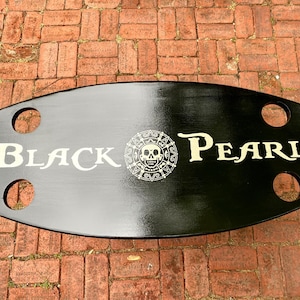 May include: Black wooden table top with a white skull and crossbones logo and the text "BLACK PEARL".