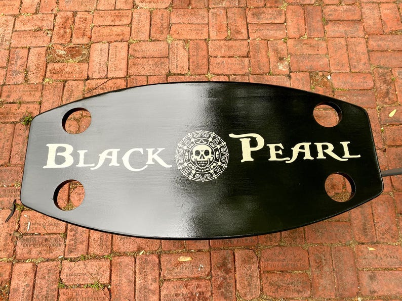 May include: Black wooden table top with a white skull and crossbones logo and the text "BLACK PEARL".