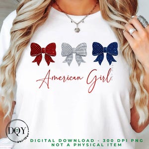Puede incluir: Camiseta blanca con tres lazos decorativos rojos, plateados y azules. El texto "American Girl" está escrito en rojo. Es una descarga digital, no un artículo físico.