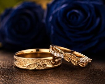 Puede incluir: Dos anillos de oro con un detallado patrón de hojas grabado en las bandas. Un anillo es una banda de oro macizo con un diseño de hojas continuo, mientras que el otro es una banda de oro más fina con pequeñas piedras claras en el motivo.