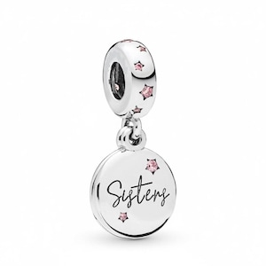 May include: A silver dangle charm featuring a circular disc engraved with the word Sisters in black script. The charm is accented with small pink star-shaped crystals on the disc and the bail, which has a polished metallic finish throughout.