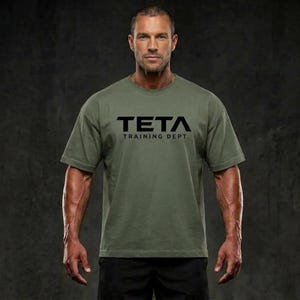 Könnte beinhalten: Ein olivgrünes Kurzarm-T-Shirt mit dem schwarzen Schriftzug TETA TRAINING DEPT. auf der Brust. Das Kleidungsstück hat einen Rundhalsausschnitt und eine Standardpassform, was ein schlichtes und funktionales Design für den Alltag bietet.