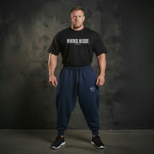May include: A black t-shirt with the text "NO WITNESS, NO EXCUSE" and navy blue sweatpants. The sweatpants have a drawstring waist and a white logo on the left leg. The person is wearing black sneakers.