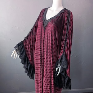 May include: A long-sleeved dress featuring a deep red and black diamond grid pattern. The garment includes a V-neckline trimmed with black lace and wide, flowing sleeves finished with ruffled black lace cuffs, creating a layered appearance.