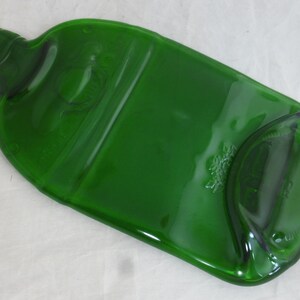May include: A green glass bottle that has been repurposed into a serving tray. The bottle has been flattened and the top has been cut off.
