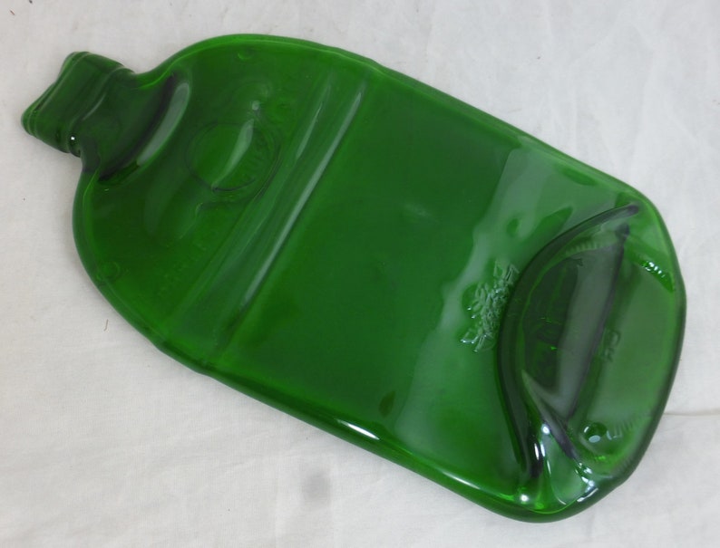 May include: A green glass bottle that has been repurposed into a serving tray. The bottle has been flattened and the top has been cut off.