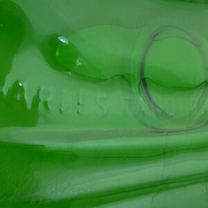 May include: A green glass bottle with a textured surface. The bottle has the words "Marles" and "Belgium" embossed on the side.