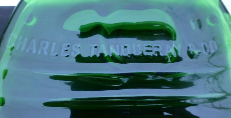 May include: A close-up of a green glass bottle with the text "CHARLES TANQUERAY & CO." embossed on the side.