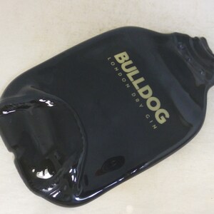 May include: Black glass bottle shaped like a gin bottle with the text "BULLDOG LONDON DRY GIN" in gold lettering.