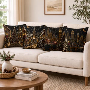 May include: Four square throw pillows featuring detailed night scenes of cityscapes and a church during winter. Each pillow displays a dark background with golden lights, snow-covered trees, and architectural landmarks under a starry sky.