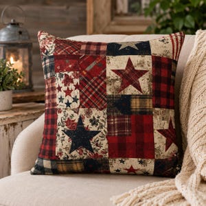 May include: Square decorative pillow with a patchwork design. The pillow features a mix of red, navy, and cream-colored fabrics with star and plaid patterns. The pillow is placed on a beige chair.