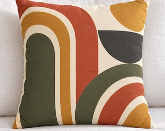 Peut inclure: Un coussin carré arborant un motif graphique composé d'arches et de demi-cercles superposés dans des tons vert olive, orange brûlé, jaune moutarde et gris anthracite sur un fond crème avec une finition en tissu texturé.
