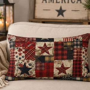 May include: Rectangular decorative pillow with a patchwork design featuring red, white, and blue stars and plaid patterns. The pillow is placed on a beige sofa, with a cozy blanket and a lantern in the background.