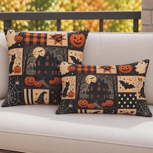 May include: Two decorative throw pillows featuring a patchwork design with Halloween motifs including a haunted house, black cats, pumpkins, ghosts, bats, spiderwebs, and a witch hat in a color palette of black, orange, and cream.