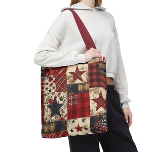 Op de afbeelding: Een patchwork tote bag met een bordeauxrode band. De tas heeft verschillende patronen, waaronder sterren, ruiten en bloemmotieven in rood, marineblauw en crèmekleur. De tas wordt door een persoon vastgehouden.